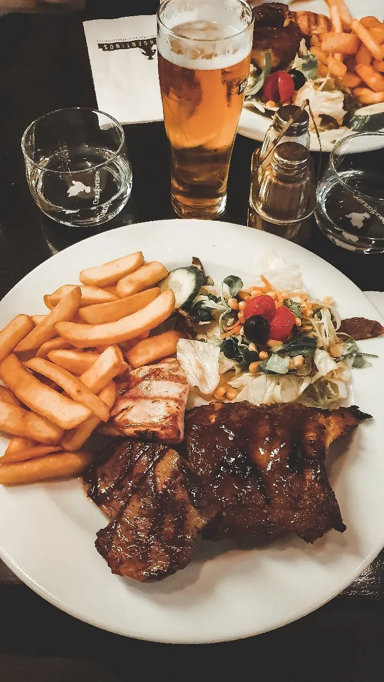 Bord met gegrild vlees, friet en salade van Argentinos Grill