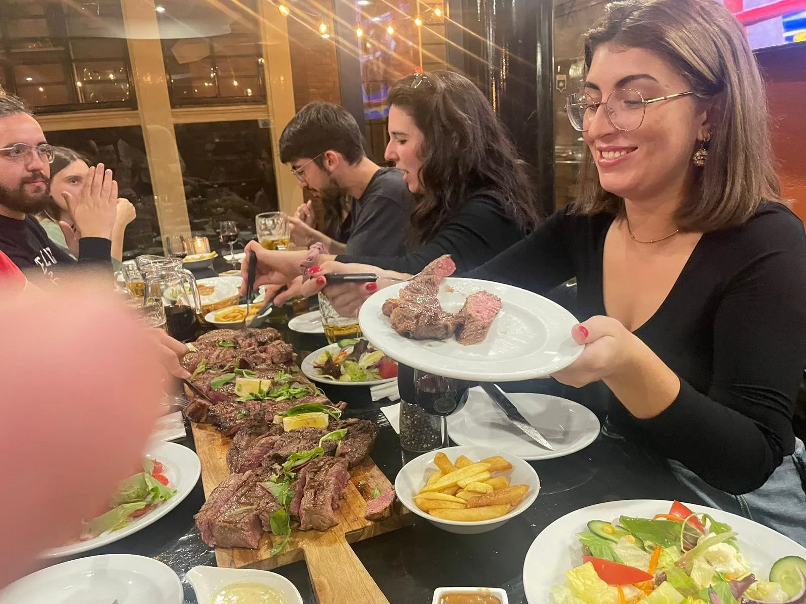Gast met een bord gegrilde steak aan tafel bij Carne Argentina