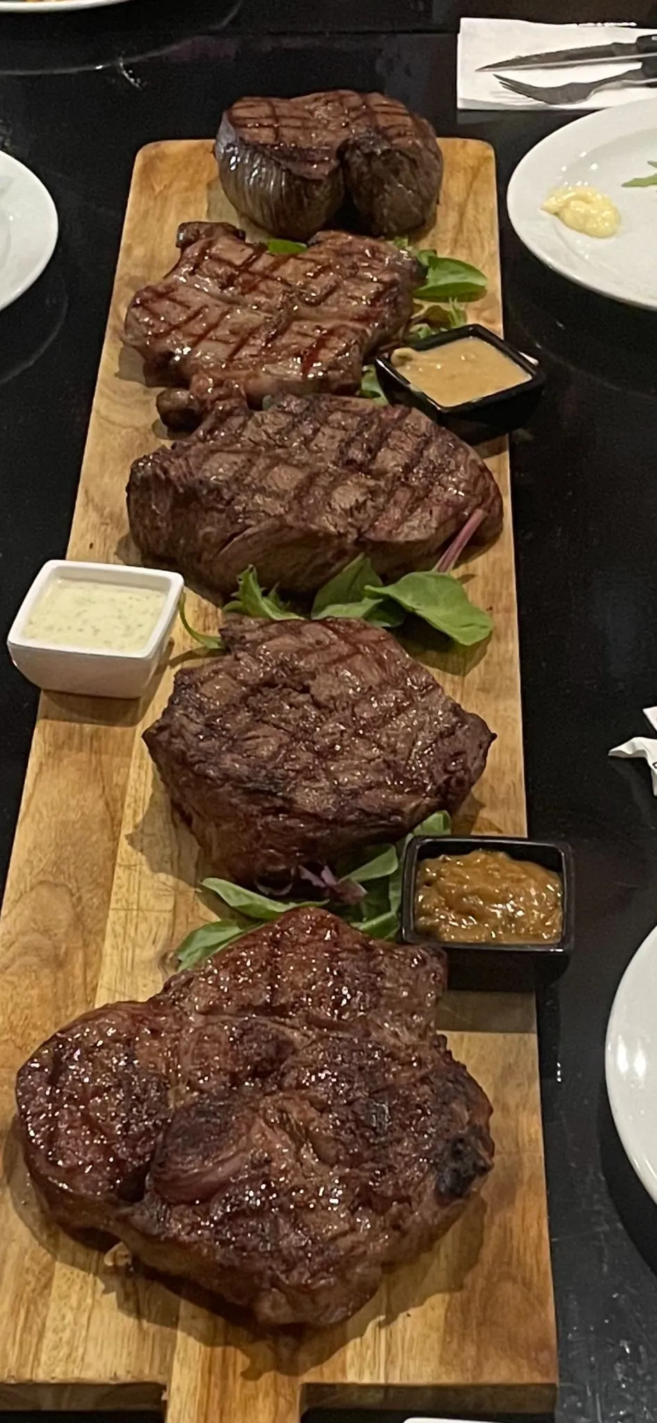 Gegrilde steaks op een plank met vier soorten saus
