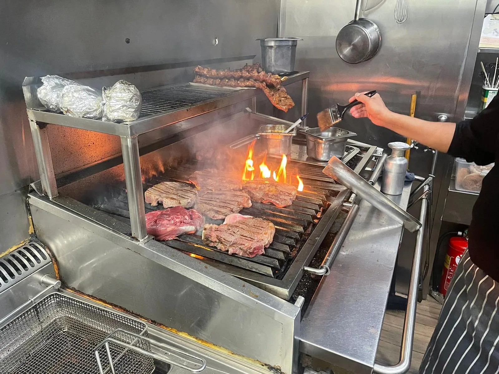 Kok grilt steaks op de parrilla in de keuken van Carne Argentina