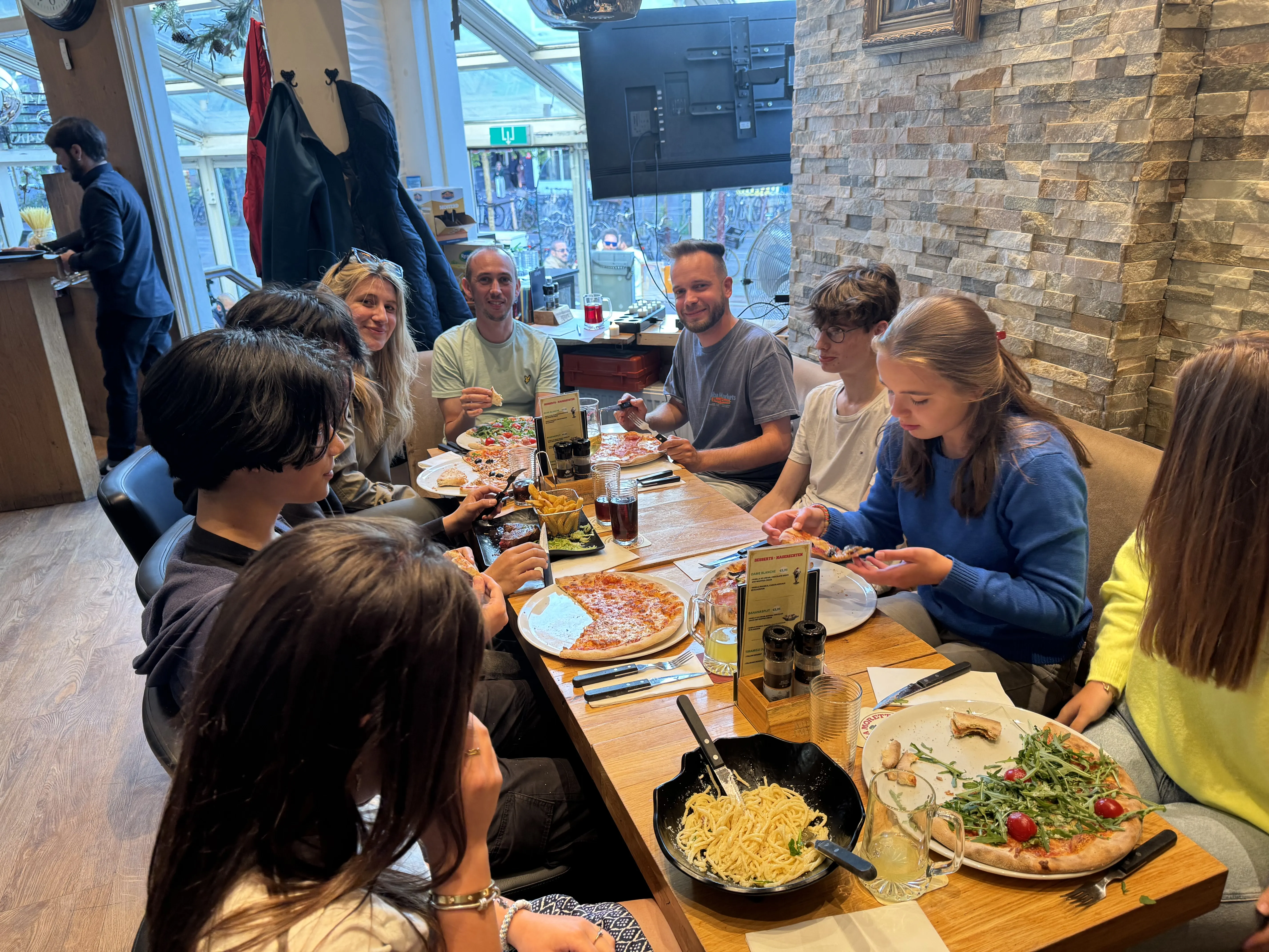 Pizza en pasta op een lange houten tafel bij Dal Toscano